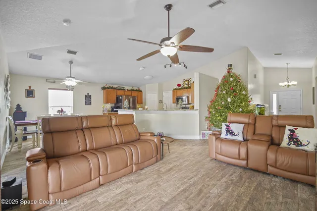 a living room with furniture kitchen view and a chandelier