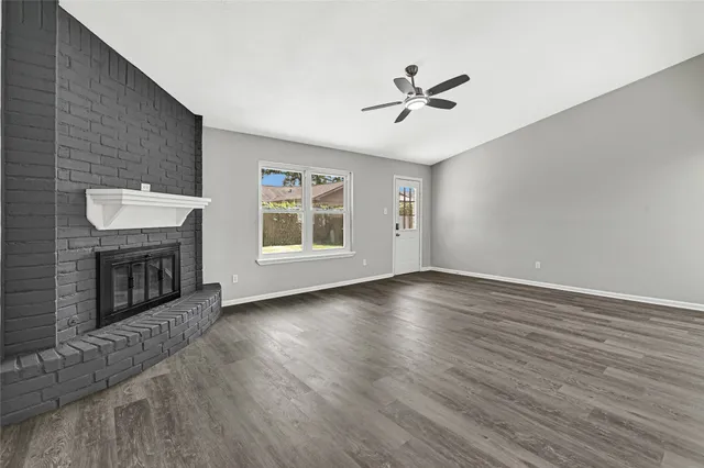 an empty room with windows fireplace and wooden floor