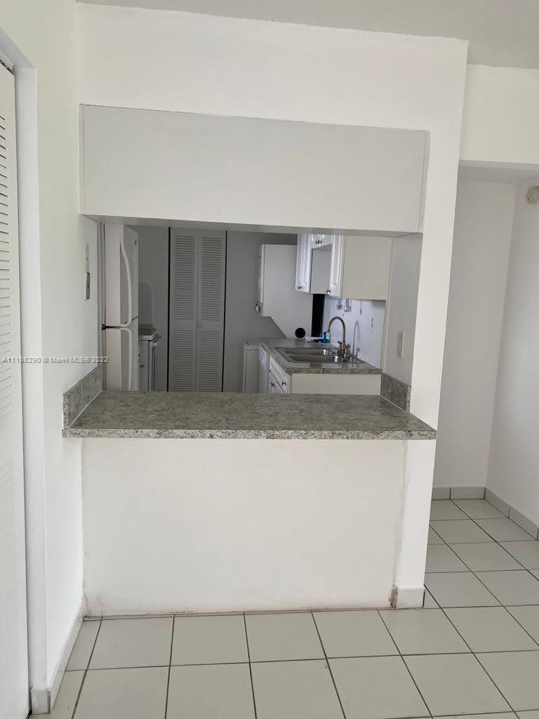 6320 Southwest 138th Court, Unit 308 Miami, FL 33183 - Photo 5 of 25 a kitchen with granite countertop a sink a stove and cabinets