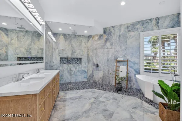 a spacious bathroom with a double vanity sink a mirror and a bathtub