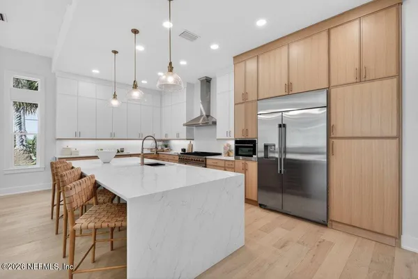 a kitchen with a table chairs wooden floors and a view of living room