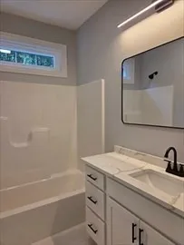 a bathroom with a granite countertop sink a mirror and a bathtub