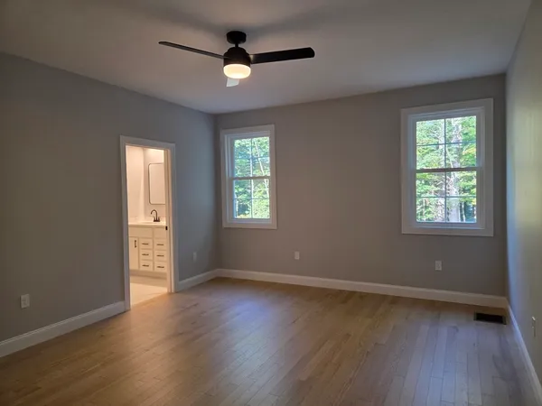 an empty room with wooden floor fan and windows