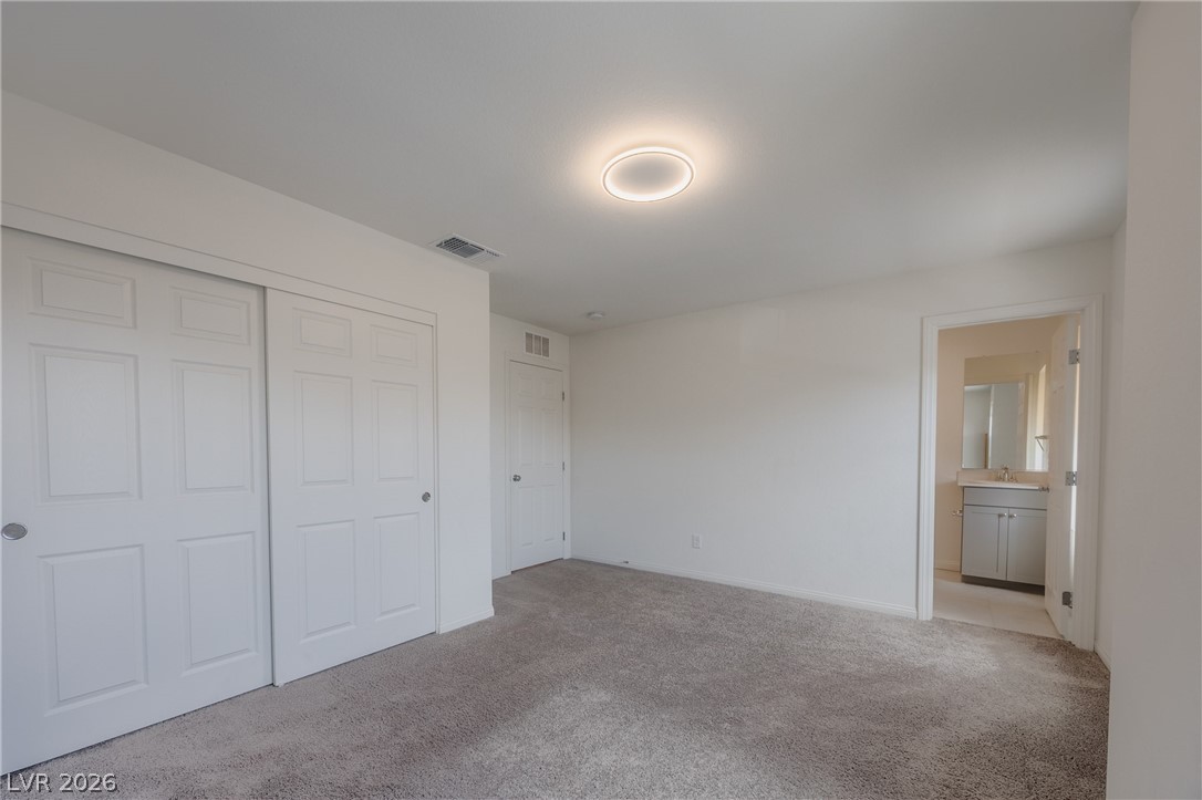5927 Coja Street Las Vegas, NV 89113 - Photo 26 of 32 Unfurnished bedroom featuring light carpet, a sink, a closet, and baseboards