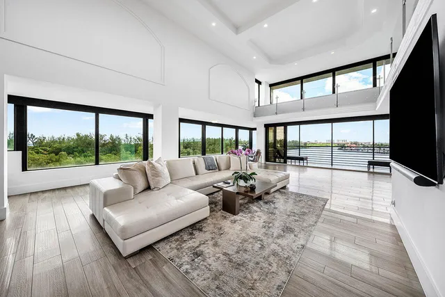 a living room with furniture a flat screen tv and a floor to ceiling window