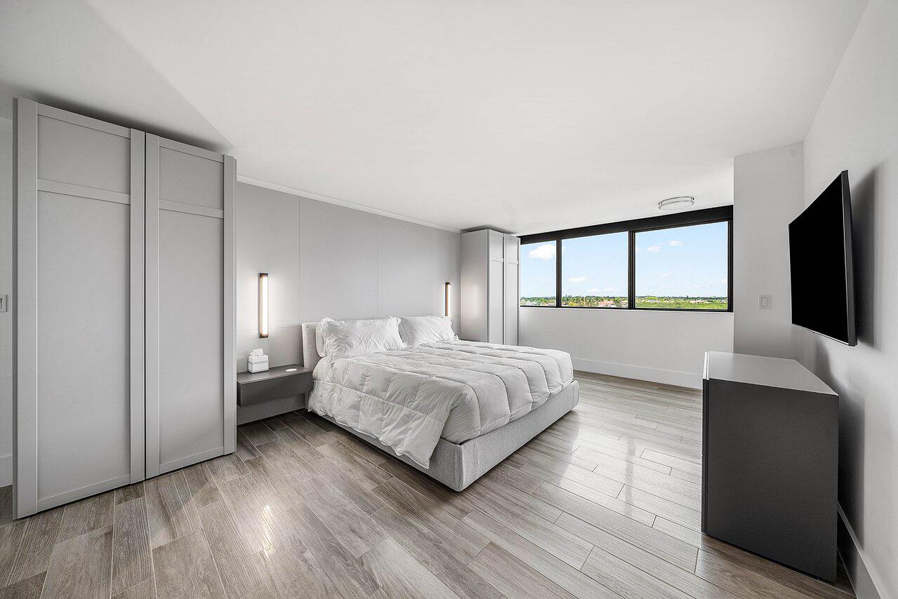 900 Northeast Spanish River Boulevard, Unit 7E Boca Raton, FL 33431 - Photo 42 of 71 a spacious bedroom with a bed and a flat tv screen on dresser