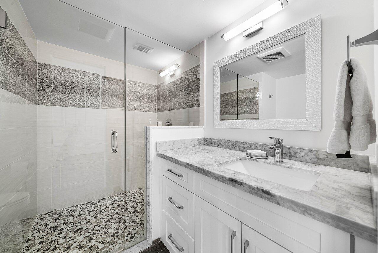 900 Northeast Spanish River Boulevard, Unit 7E Boca Raton, FL 33431 - Photo 46 of 71 a bathroom with a granite countertop sink a mirror and shower