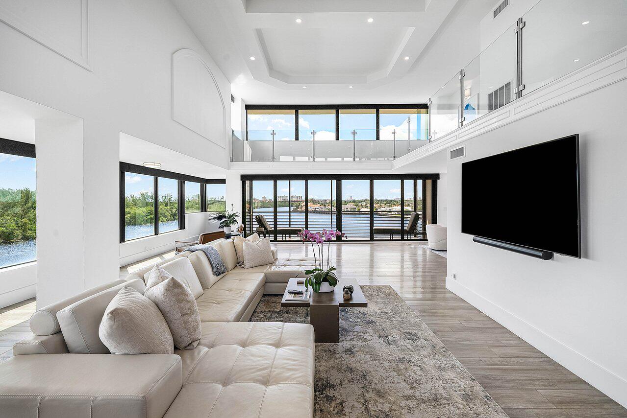 900 Northeast Spanish River Boulevard, Unit 7E Boca Raton, FL 33431 - Photo 5 of 71 a living room with furniture a flat screen tv and a floor to ceiling window