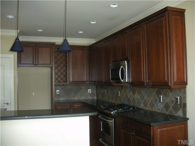 658 Democracy Street Raleigh, NC 27603 - Photo 9 of 25 a kitchen with granite countertop stainless steel appliances a stove microwave and cabinets