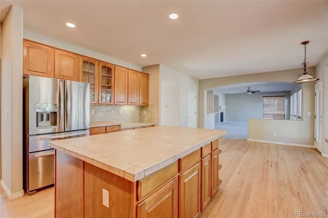 a kitchen with stainless steel appliances granite countertop a refrigerator a sink dishwasher and a stove with wooden floors