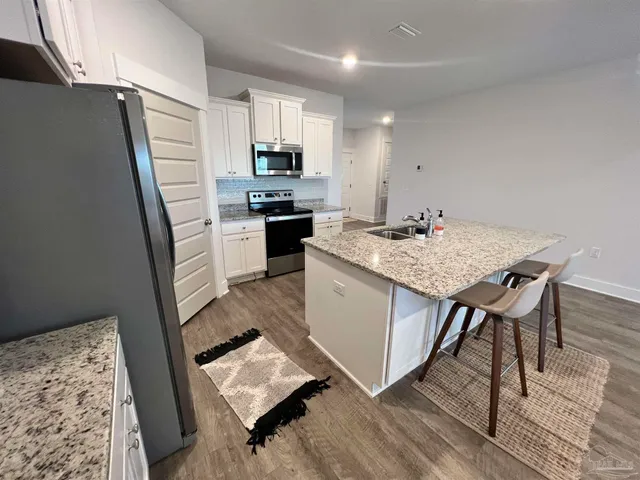 a kitchen with stainless steel appliances granite countertop a sink stove refrigerator and a granite counter top