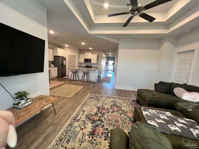 a living room with stainless steel appliances kitchen island granite countertop a couch wooden floor and a dining table