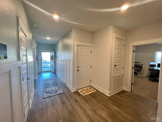 a view of a hallway with wooden floor and a bathroom