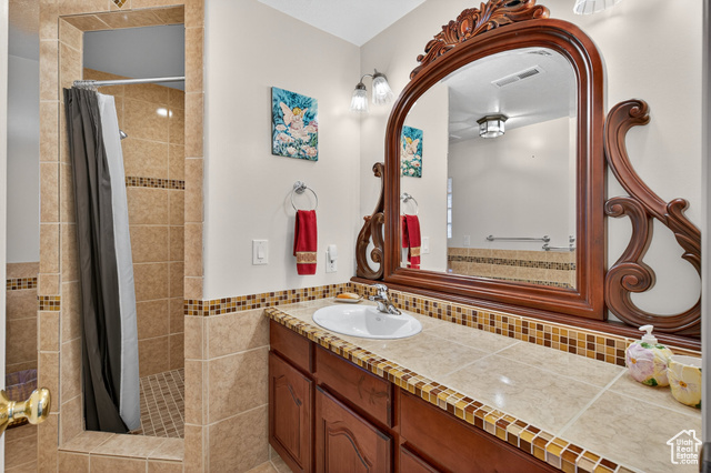 4768 East Hickman Canyon Road Stockton, UT 84071 - Photo 45 of 85 Basement bathroom with a tile shower, vanity, tile walls, and light tile patterned flooring.