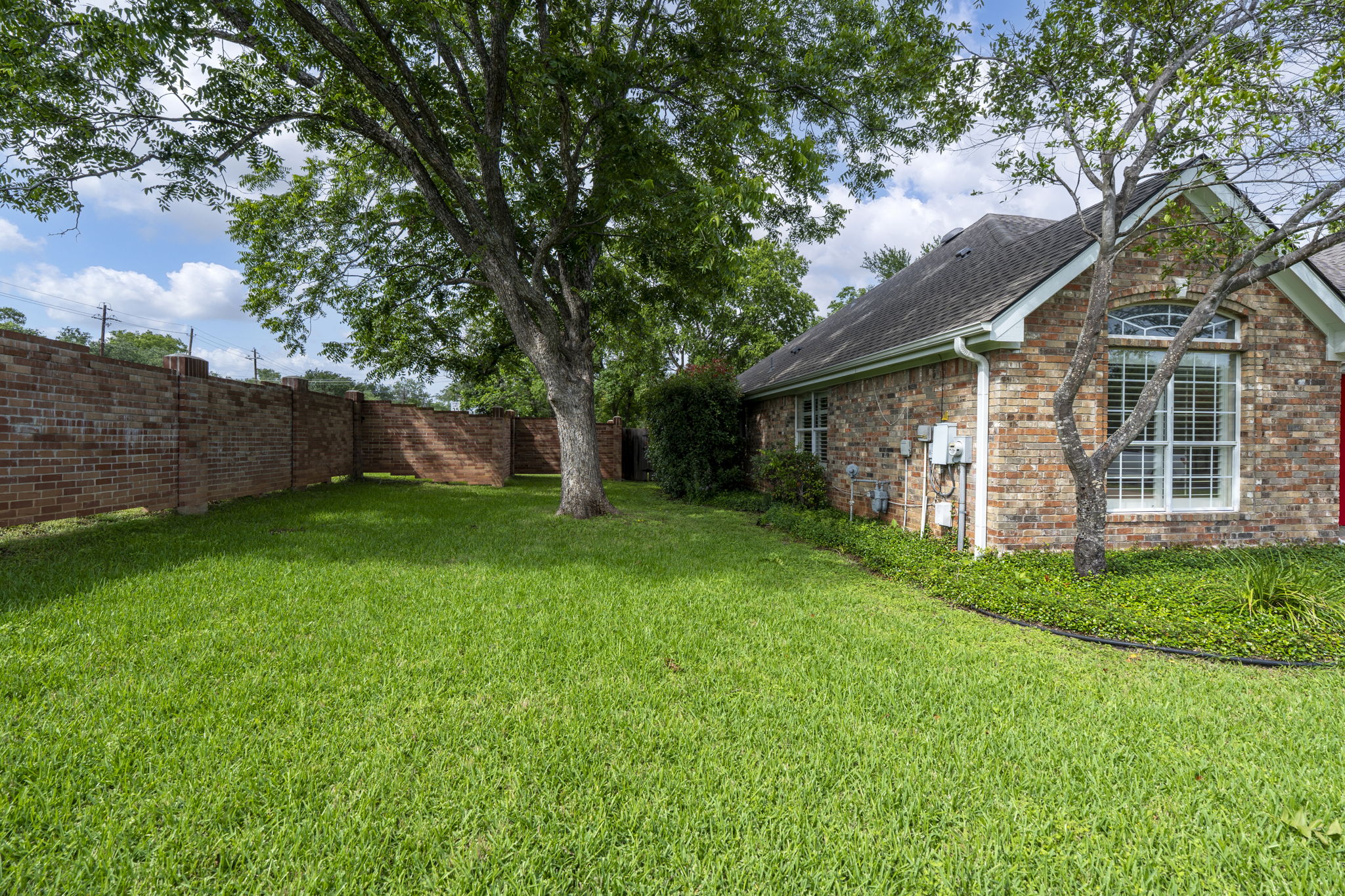 7172 Ridge Oak Road Austin, TX 78749 - Photo 4 of 40 A well-maintained lawn stretches beside a brick-faced home, offering ample outdoor space.