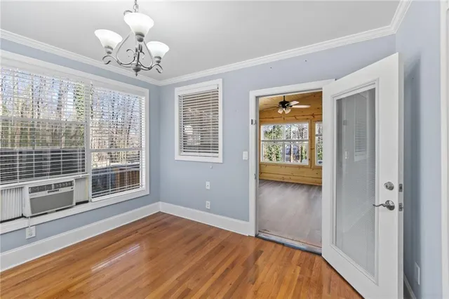 a view of an empty room with a window and wooden floor