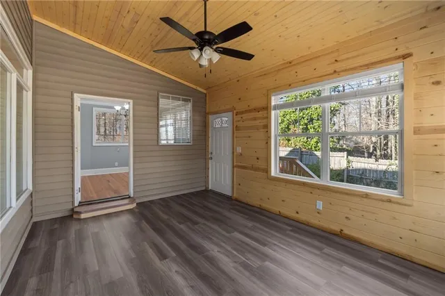 an empty room with windows fireplace and fan