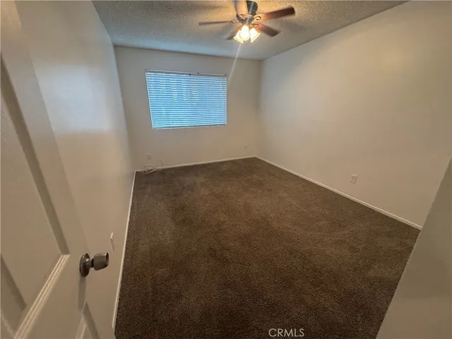 an empty room with a chandelier fan and windows