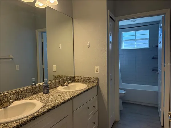a bathroom with a granite countertop sink a mirror and a bathtub