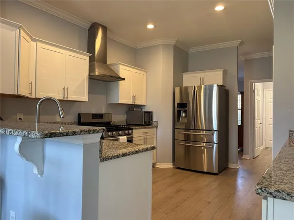 a kitchen with stainless steel appliances granite countertop a refrigerator a sink dishwasher a stove and a refrigerator