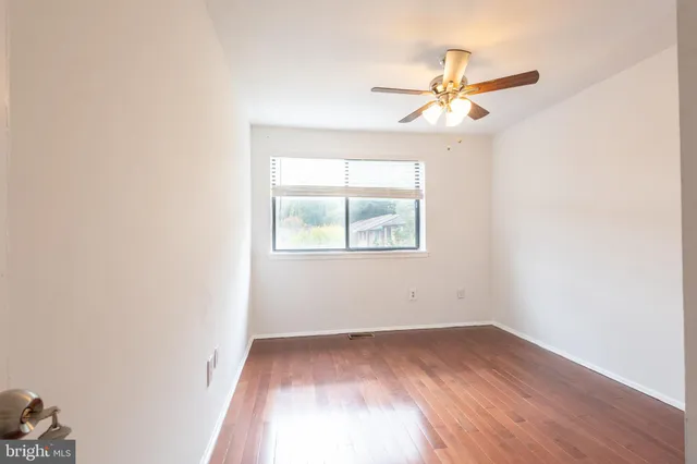 an empty room with a window and a fan
