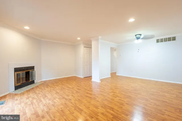 a view of an empty room with wooden floor and a fireplace