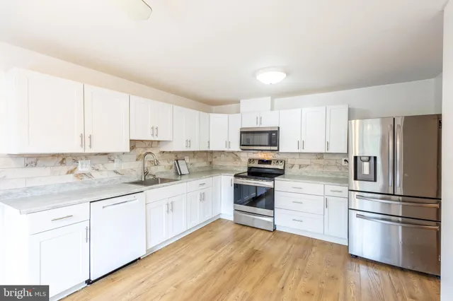 a kitchen with granite countertop white cabinets and stainless steel appliances