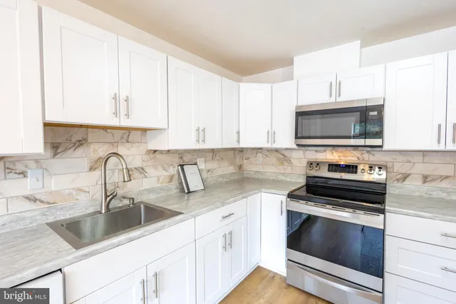 a kitchen with granite countertop a sink stove and microwave