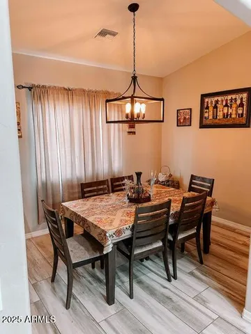 a view of a dining room and livingroom with furniture wooden floor a rug and a chandelier