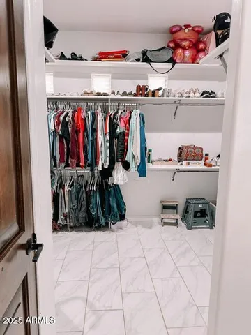 a view of walk in closet with clothes and shoes