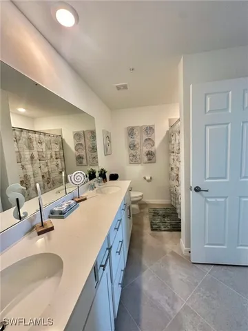 a large bathroom with a granite countertop double vanity sink a mirror and a bathtub