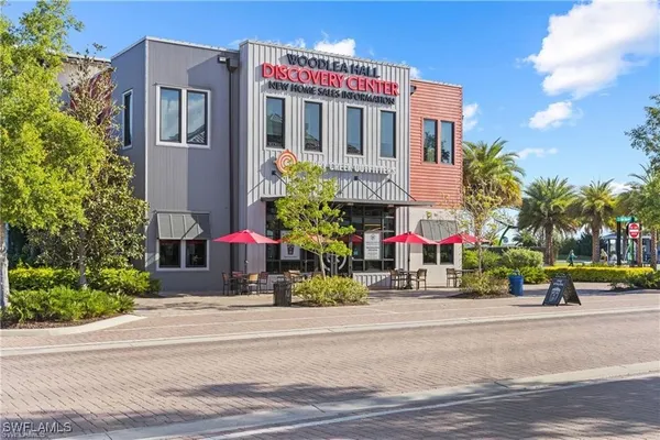 a front view of multi story residential apartment building with yard and retail shops