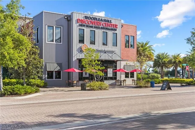 a front view of multi story residential apartment building with yard and retail shops