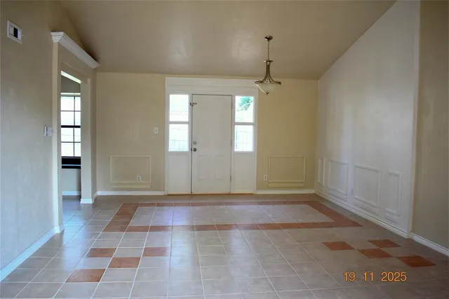 a view of an empty room with window and chandelier fan
