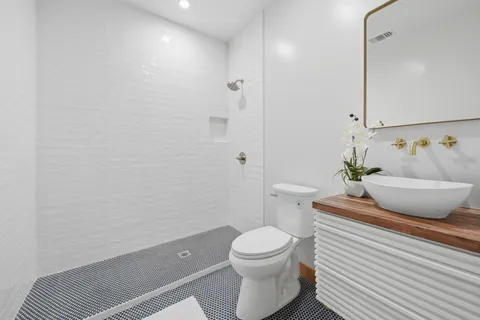 a bathroom with a granite countertop sink a toilet and shower