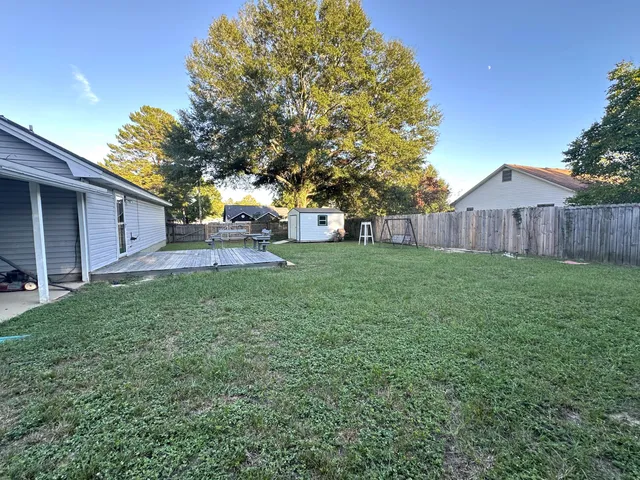 a view of a yard in front of a house with large tree