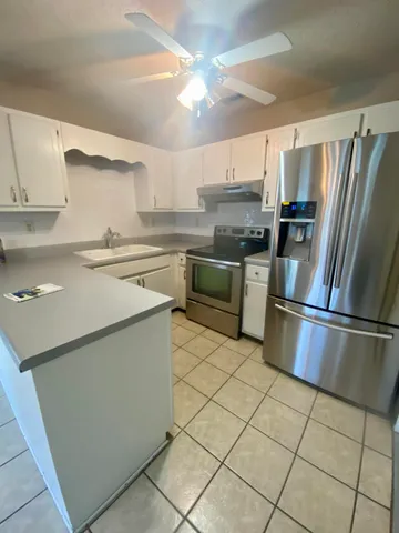 a view of an empty room with window and chandelier fan