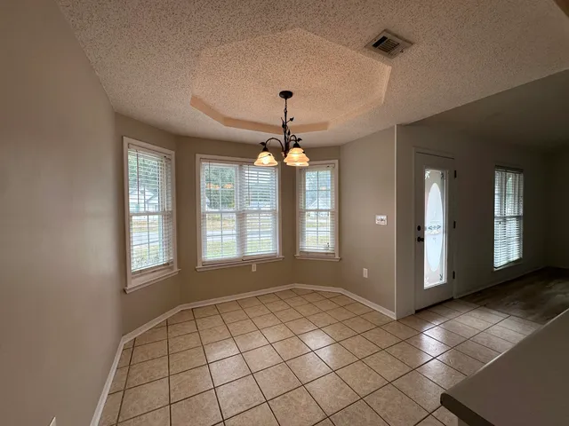 a view of an empty room with a window and chandelier