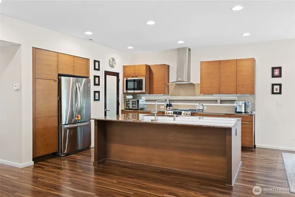 a kitchen with stainless steel appliances granite countertop a refrigerator a stove and a sink