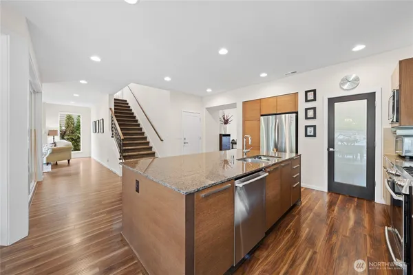 a kitchen with stainless steel appliances granite countertop a sink and wooden floor
