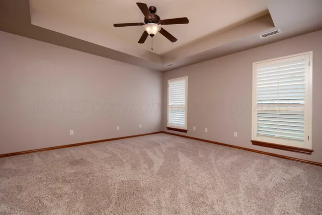 an empty room with windows and fan