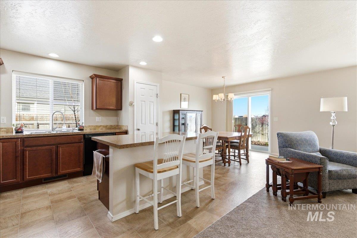 13622 Orlando Street Caldwell, ID 83607 - Photo 4 of 16 Kitchen featuring a kitchen bar, a center island, a textured ceiling, black dishwasher, and suspended lighting