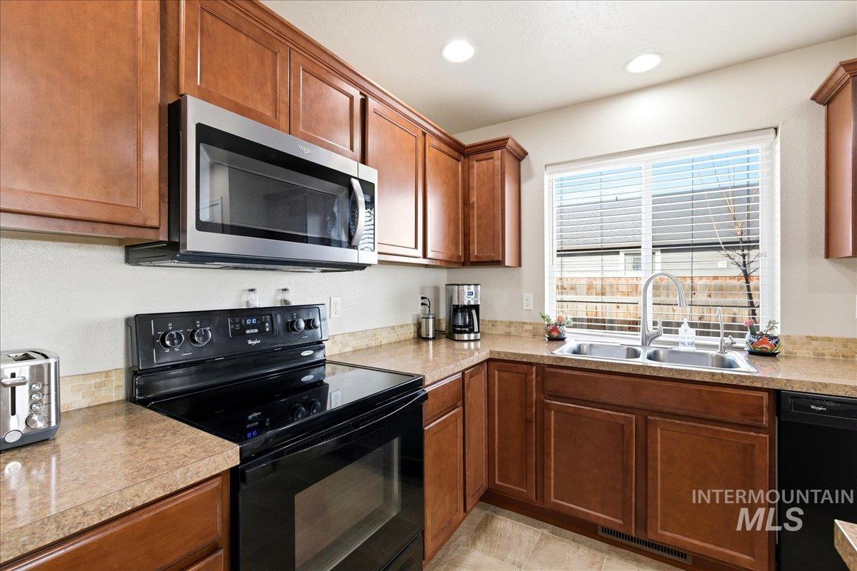 13622 Orlando Street Caldwell, ID 83607 - Photo 5 of 16 Kitchen with black appliances, wood finish cabinetry, light countertops, and recessed lighting