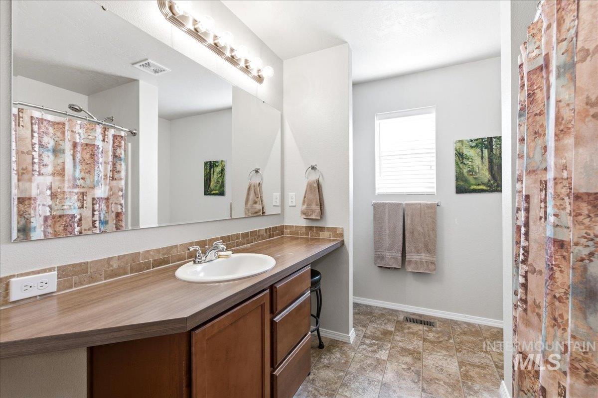 13622 Orlando Street Caldwell, ID 83607 - Photo 8 of 16 Full bath featuring curtained shower, vanity, and stone finish floors
