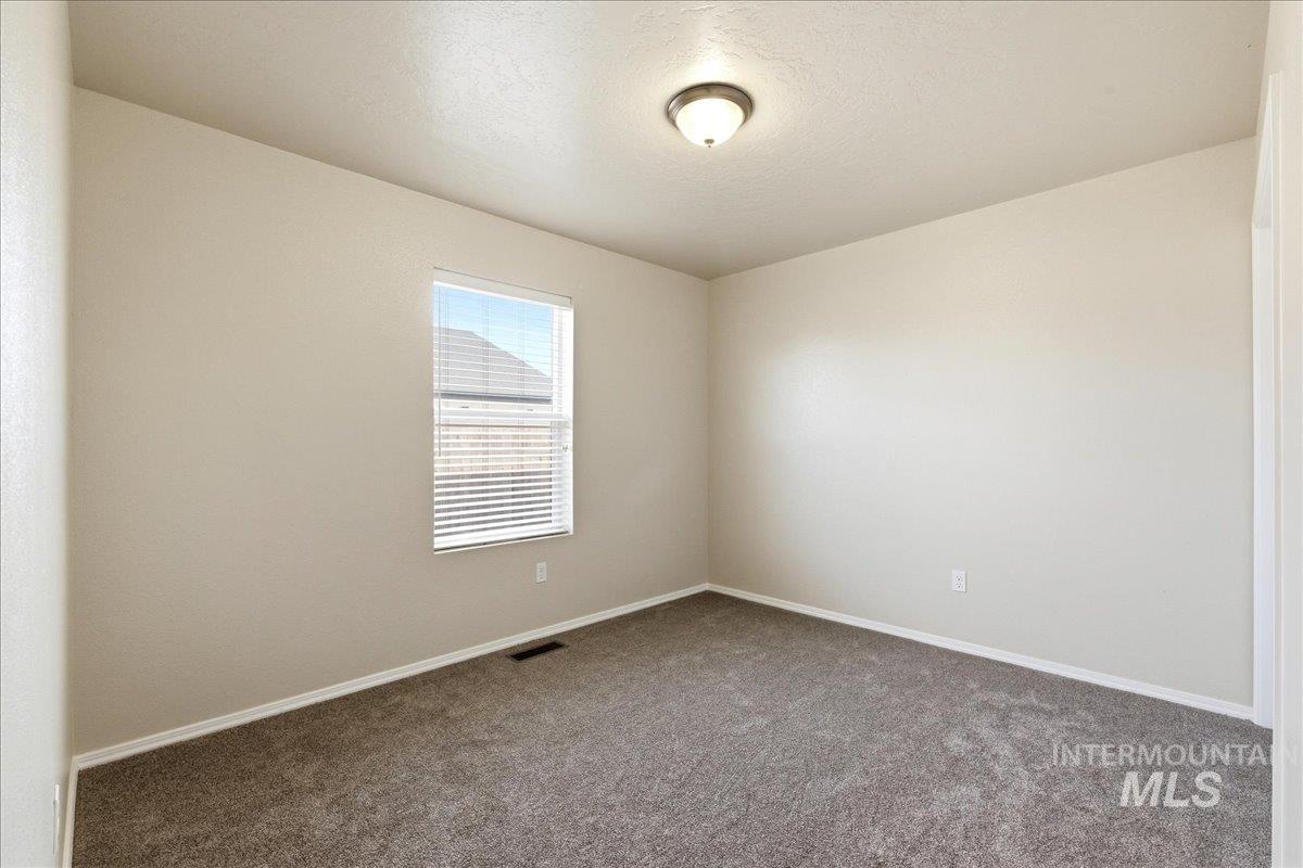 13622 Orlando Street Caldwell, ID 83607 - Photo 9 of 16 Empty room featuring dark colored carpet and a textured ceiling