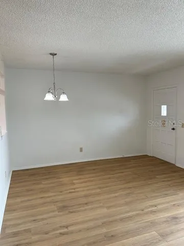 a view of an empty room with wooden floor and chandelier