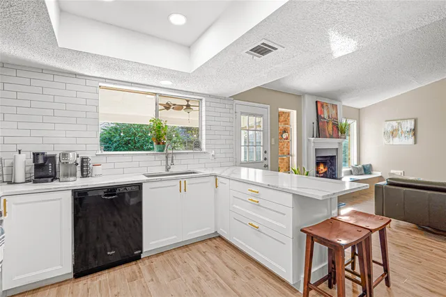 a kitchen with stainless steel appliances a stove a sink dishwasher a refrigerator with a dining table and chairs