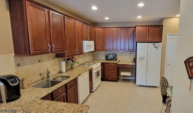a kitchen with stainless steel appliances granite countertop a sink stove refrigerator and cabinets