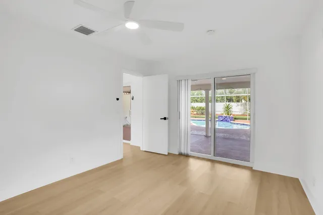 a view of an empty room with wooden floor and window