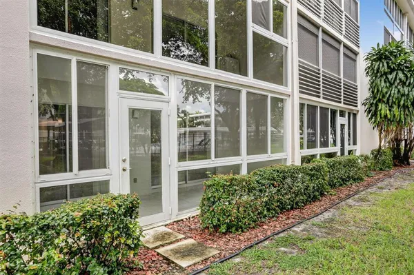 front view of a brick house with a large window and potted plants